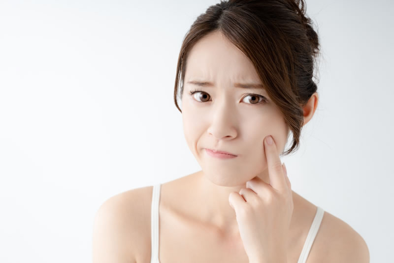 頬に手を当てて肌を気にしている女性