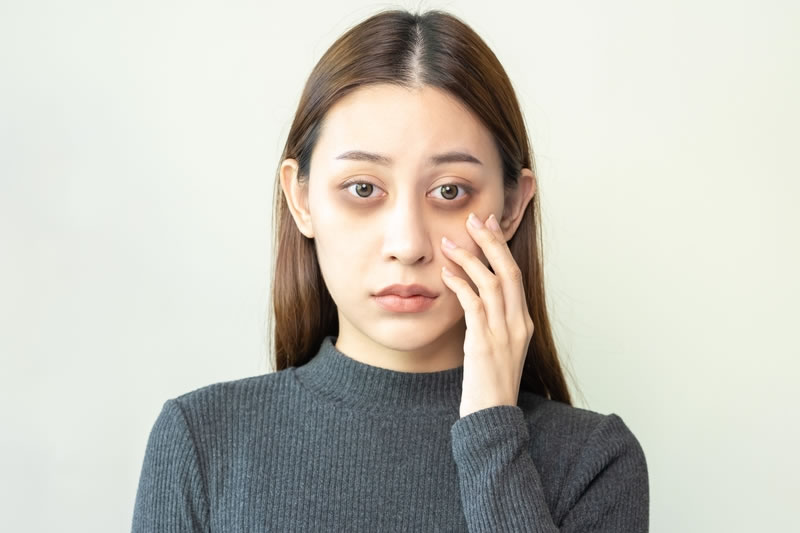 目元を指で確かめている女性。まぶたのラインが気になるときのイメージ