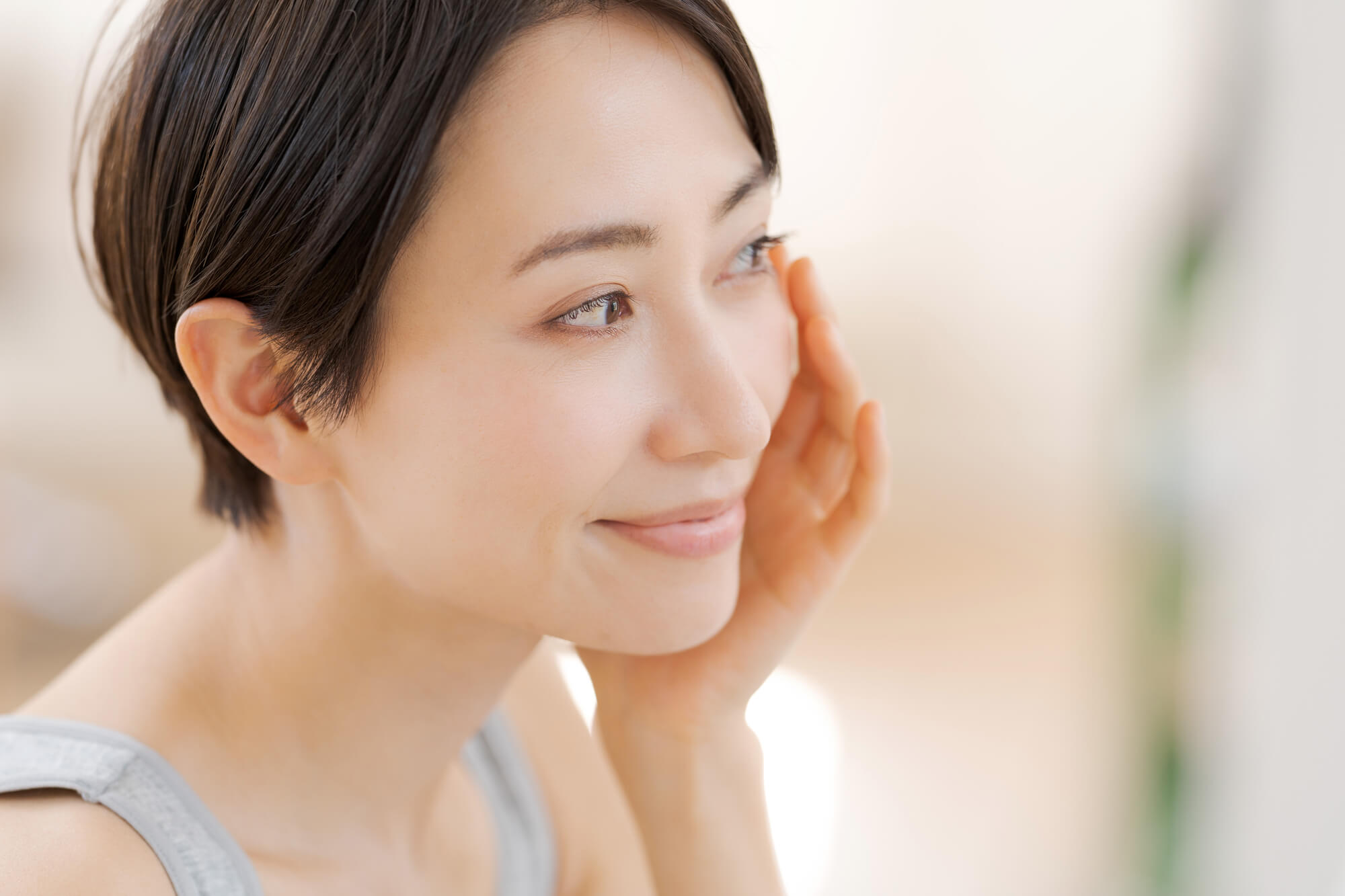 フェイスラインのたるみを手で確かめている女性