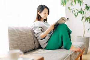 自宅のソファで穏やかに過ごす女性。美容整形後のダウンタイム中の過ごし方のイメージ
