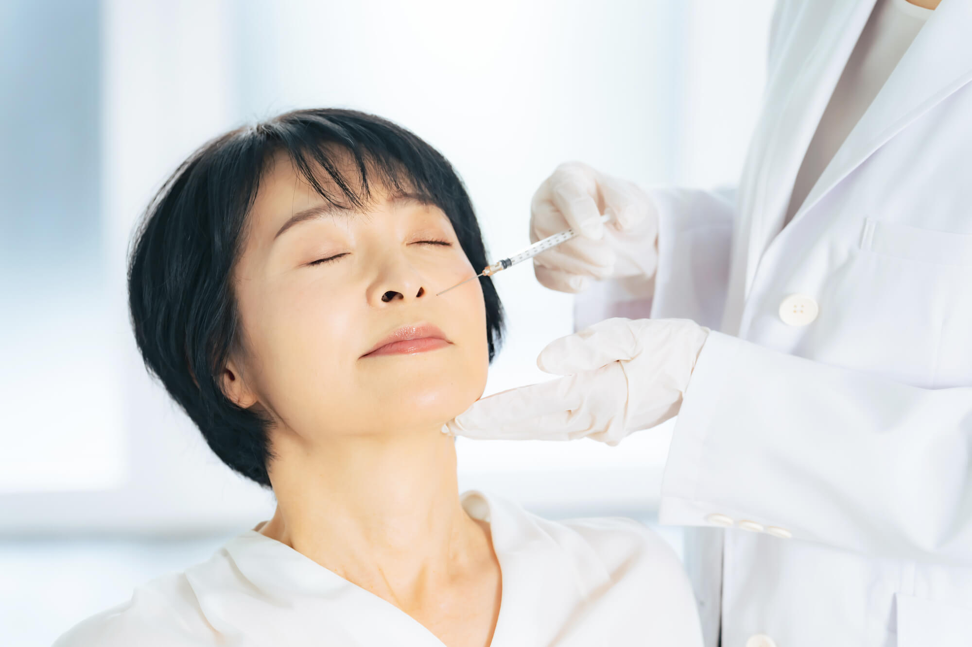 目を閉じた女性の頬に医師が注射を行う様子。年齢に伴う肌質の変化に対する肌育注射のイメージ