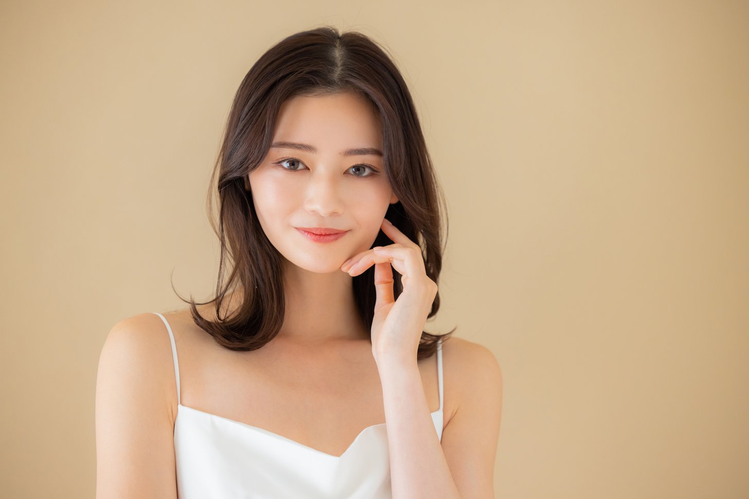 頬に手のひらを当ててスキンケアをする女性。糸リフト後のメイクや洗顔の再開のイメージ