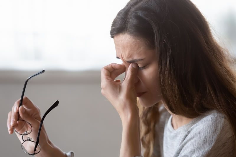 疲れ目で目をマッサージしている女性