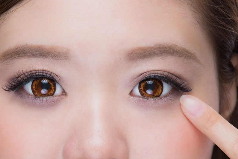 目もとを指さしている女性